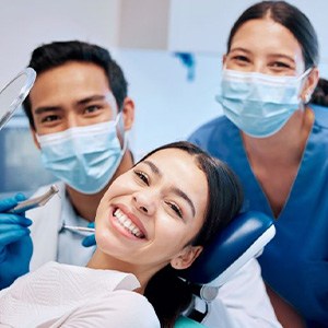 Happy patient posing with her dental care team