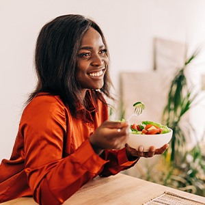 Woman smiling while eating salad at home