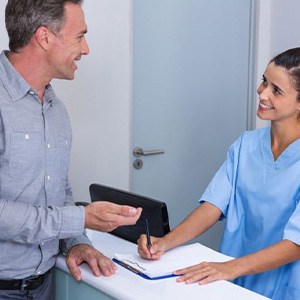 Dental team member assisting patient at front desk