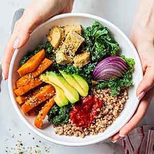 A closeup of a bowl of healthy foods held by a woman