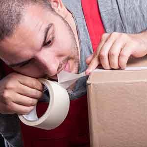 A man tearing tape packaging with his teeth