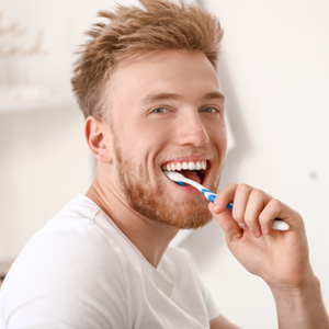 Man smiling while brushing his teeth