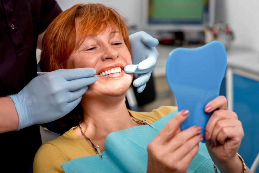 A woman smiling at the dentist after getting new dentures