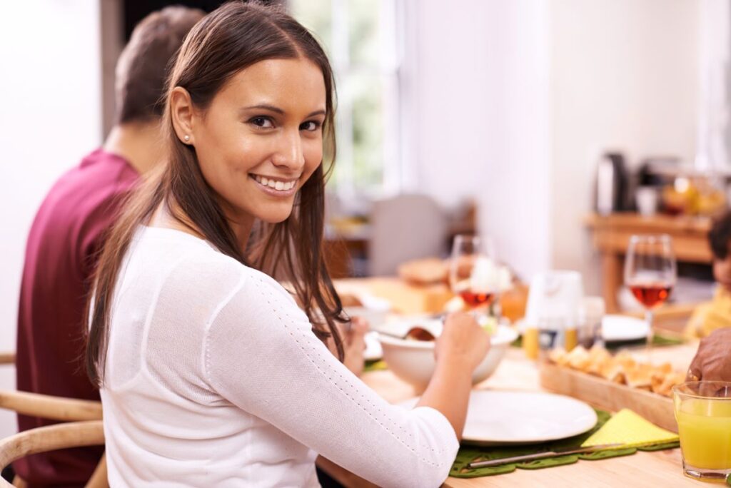 A woman smiling at Thanksgiving dinner.